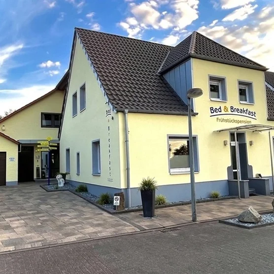 pension-legden-unterkunft-muensterland Moderne Außenansicht der Pension Gödde in Legden im Münsterland mit Parkplatz und Fahrradgarage.