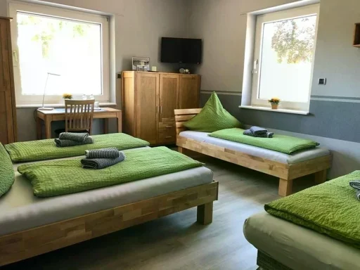 Helles Mehrbettzimmer mit Vollholzmöbeln, TV und Schreibtisch zum Übernachten in der Pension - Gästehaus Legden.