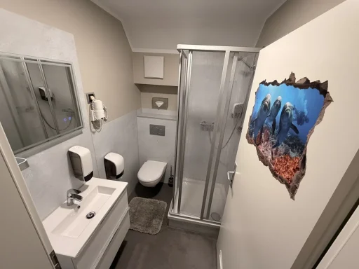 Modernes, sauberes Badezimmer der Pension in Legden mit Dusche, WC, Waschbecken und hellen Fliesen.