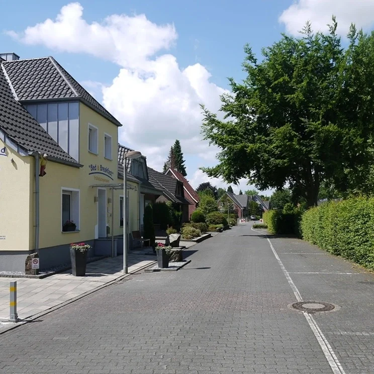 Ruhig und dennoch zentral gelegen: Ein Blick auf unser Gästehaus in Legden. Die verkehrsberuhigte Straße und die direkt anliegenden Stellflächen bieten Ihnen eine entspannte Anreise – auch mit größeren Transportern oder Firmenfahrzeugen. Genießen Sie eine erholsame Zeit in einer angenehmen Nachbarschaft. Großer, befestigter Parkplatz der Pension in Legden mit ausreichend Platz für Transporter und Handwerker-Fahrzeuge.